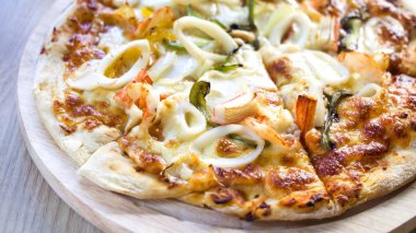 Deniz ürünleri (karides, kalamar, Yengeç, peynir ve benzeri) ahşap tahta (16:9 fotoğraf üzerinde lezzetli sıcak çıtır pizza)
