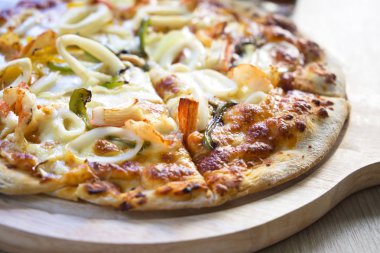 Deniz ürünleri (karides, kalamar, Yengeç, peynir ve benzeri) ahşap oyun tahtası ile lezzetli sıcak çıtır pizza