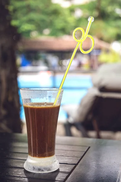 traditional Vietnamese coffee with condensed milk in a tall glass near the swimming pool