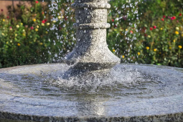 Nahaufnahme eines fallenden Wassers im Brunnen mit hellen bunten Blumen auf einem Hintergrund — Stockfoto