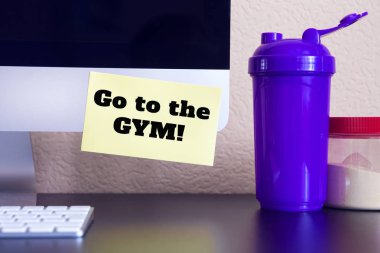 uyarı mektubu sarı etiket Not metin ile modern bilgisayar: spor salonuna gitmek! (shaker ve spor takviyeleri masaya)