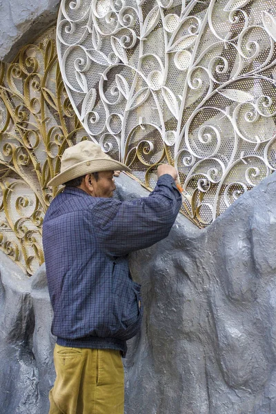 A man paints heart-shaped grating of wrought iron on the gray wall, Vietnam, Dalat city 2018-01-11 — Stock Photo, Image