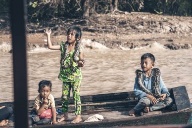 Kamboçya 2019-12-27 'deki Tonle Sap gölünde büyük piton yılanlı çocuklar. Suda yüzen köy.