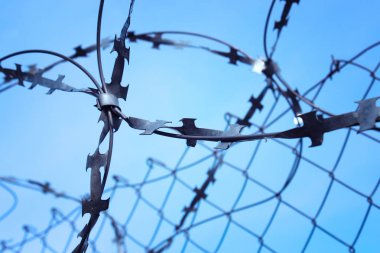 Mavi gökyüzü arka plan üzerinde rulo dikenli teller ile kablolu çit.