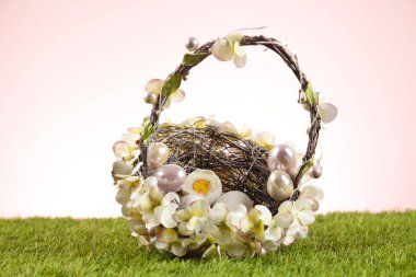 Hasır sepetteki paskalya yumurtaları yeşil çimen arka planını doldurdu 