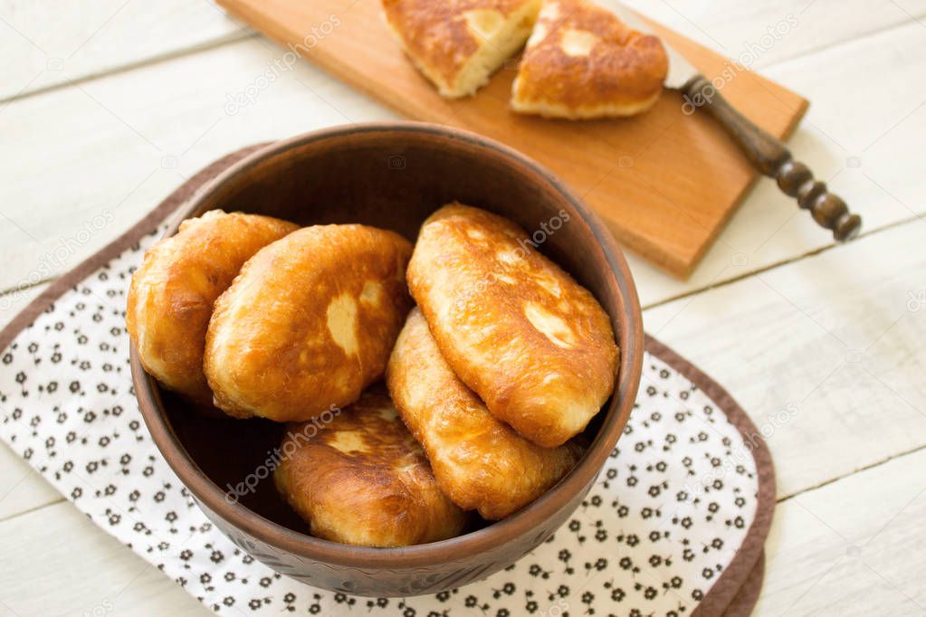 Traditional homemade fried patties or pies in a ceramic bowl. Fried Russian pies made of yeast dough in a rustic style.
