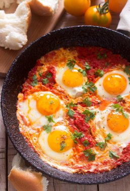 Ahşap bir masa üzerinde ekmek ile Shakshuka. Orta Doğu geleneksel çanak. Ev yapımı. Seçici odak.