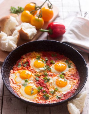 Ahşap bir masa üzerinde ekmek ile Shakshuka. Orta Doğu geleneksel çanak. Ev yapımı. Seçici odak.
