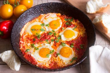 Ahşap bir masa üzerinde ekmek ile Shakshuka. Orta Doğu geleneksel çanak. Ev yapımı. Seçici odak.