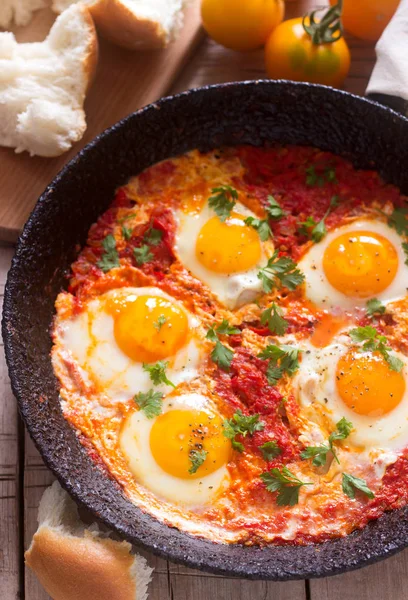 Ahşap bir masa üzerinde ekmek ile Shakshuka. Orta Doğu geleneksel çanak. Ev yapımı. Seçici odak.