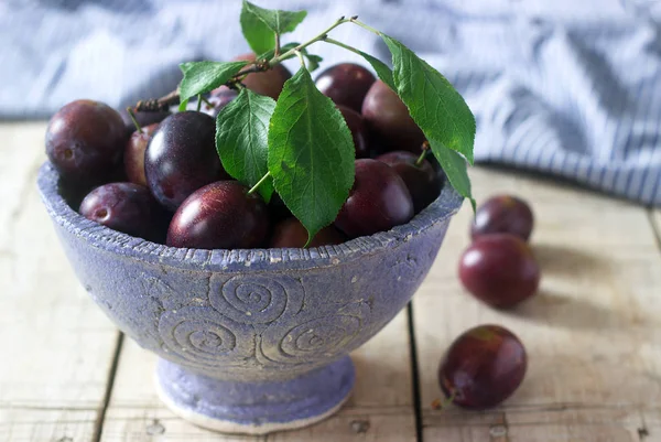 Prunes dans un bol d'argile sur une table en bois. Style rustique, accent sélectif . — Photo