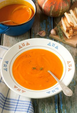 Ahşap arka plan üzerinde beyaz bir tabak içinde kabak kremalı çorba. Rustik tarzı, seçici odak.