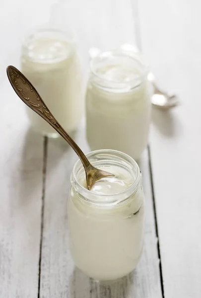 Homemade yogurt in a glass jar on a wooden table. Rustic style, selective focus. — Stock Photo, Image