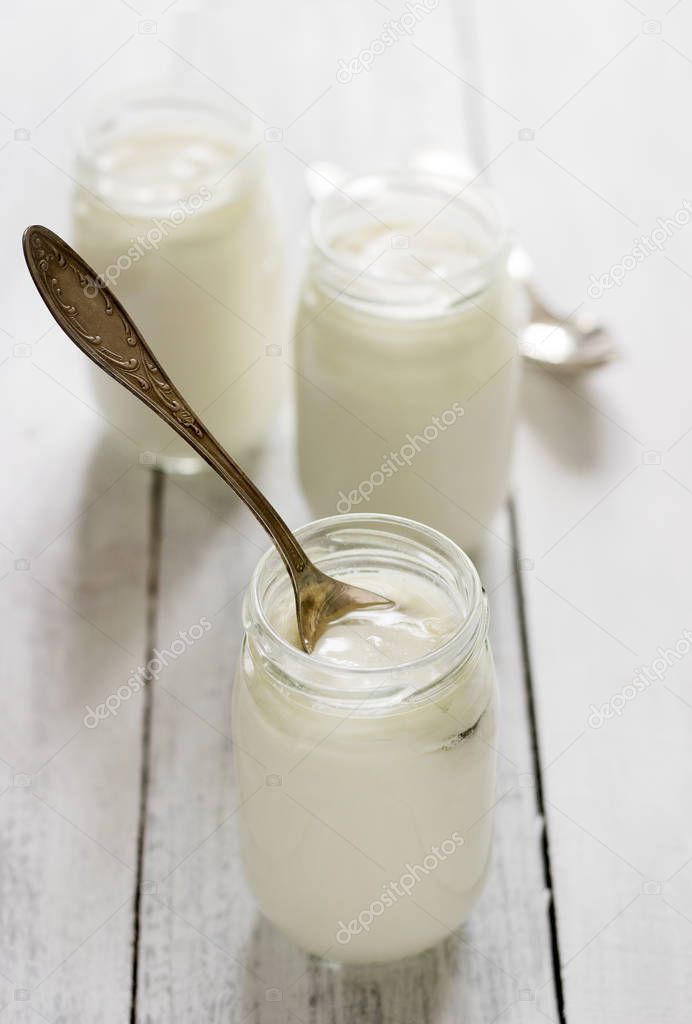 Homemade yogurt in a glass jar on a wooden table. Rustic style, selective focus.