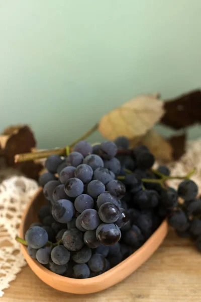 Grapes in a clay plate on a wooden background. Rustic style, selective focus. — Stock Photo, Image