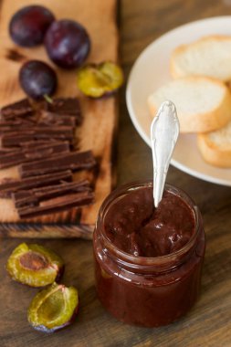 Bir cam kavanoz, taze Erik ve ahşap bir yüzey üzerinde çikolata parçalarını Erik çikolatalı reçel.