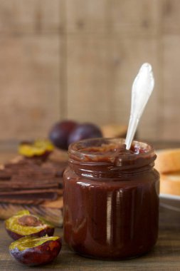Bir cam kavanoz, taze Erik ve ahşap bir yüzey üzerinde çikolata parçalarını Erik çikolatalı reçel.