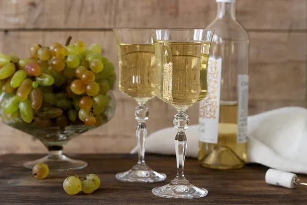 Vino bianco con calici di vetro e grappoli d'uva su fondo ligneo . — Foto Stock