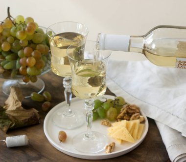 Gözlüklü beyaz şarap ve bir şişe şarap ile bir snack - peynir, ceviz ve üzüm. Rustik tarzı.