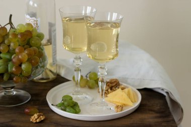 Gözlüklü beyaz şarap ve bir şişe şarap ile bir snack - peynir, ceviz ve üzüm. Rustik tarzı.