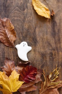 Cadılar Bayramı, hayalet gingerbread dekore edilmiş ahşap arka plan üzerinde sonbahar yaprakları ile.