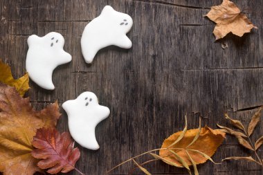 Cadılar Bayramı, hayalet gingerbread dekore edilmiş ahşap arka plan üzerinde sonbahar yaprakları ile.