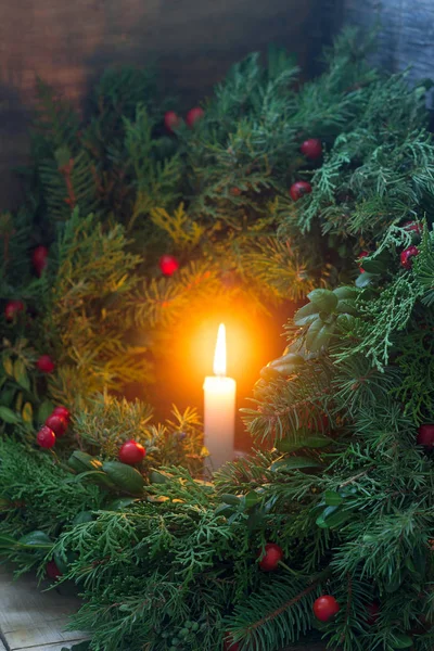 Una corona di Natale fatta di rami di abete, ginepro, tuja, bosso e frutti di bosco di rose selvatiche. Ghirlanda con candele accese . — Foto Stock