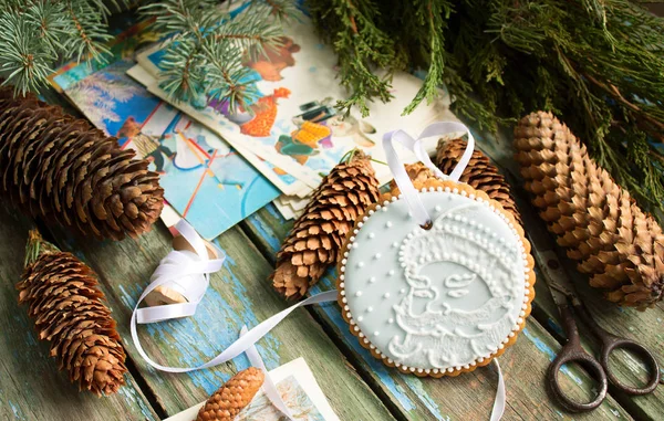 Peperkoek met een afbeelding van de Kerstman, vuren kegels, takken en postkaarten op een houten achtergrond. Kerst decor. — Stockfoto