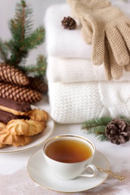 Çay ve bisküvi içinde belgili tanımlık geçmiş halı ya da kazak, koni ve köknar dalı ile kış kompozisyon.