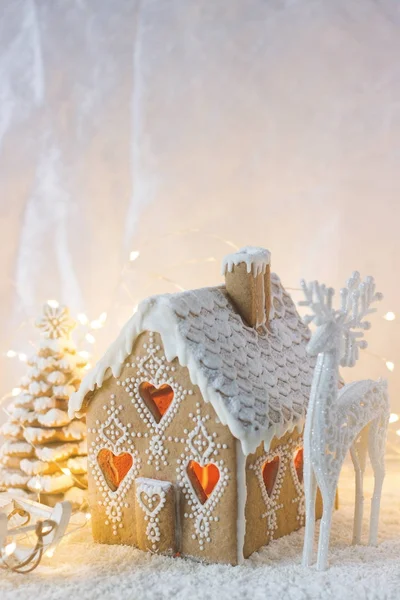Peperkoek huis, kerstbomen en een figuur van een hert op een lichte achtergrond. Bokeh-effect. — Stockfoto