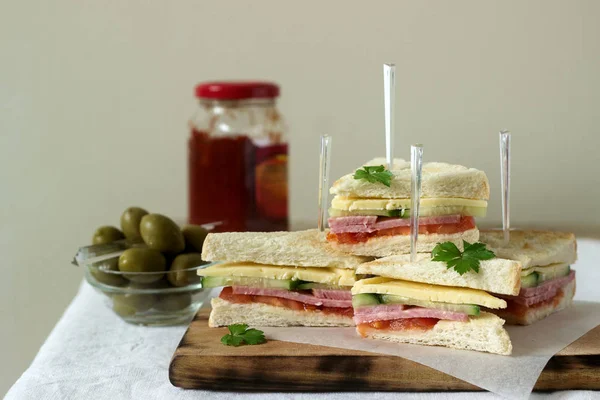 Sandwiches with sausage, meat, cheese and fresh vegetables on a table with olives and ketchup. — Stock Photo, Image