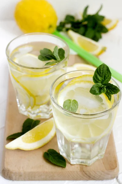 Limonade mit Zitronenscheiben, Minze und Eis und Zitronen auf hellem Betongrund. rustikaler Stil. — Stockfoto