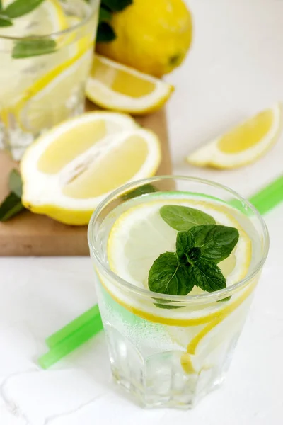 Lemonad med citronskivor, mynta och is och citroner på en konkret bakgrund. Rustik stil. — Stockfoto