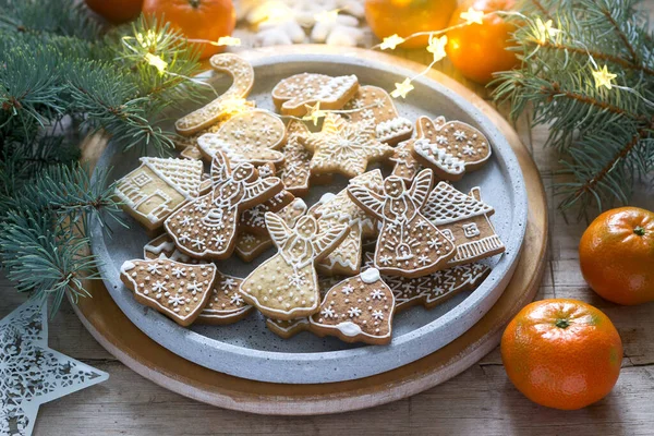 Gingerbread cookies on a concrete tray on a winter background with tangerines, fir branches and a garland. — Stock Photo, Image