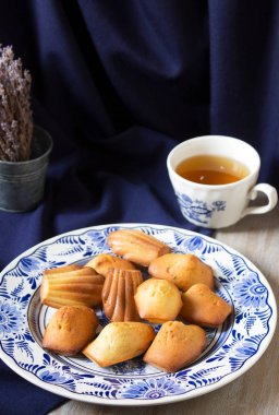 Mavi arka planda porselen bir tabakta lavanta madeleine. Kırsal biçim.