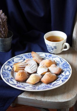 Mavi arka planda porselen bir tabakta lavanta madeleine. Kırsal biçim.