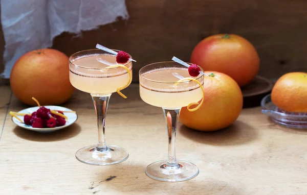 Champagne cocktail with grapefruit juice, garnished with zest and raspberries. Rustic style. — Stock Photo, Image