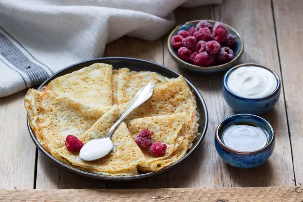 Panqueques servidos con crema agria, frambuesas y miel. El plato tradicional en Carnaval y Maslenitsa . —  Fotos de Stock