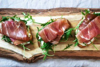 Traditional italian appetizer bruschetta of toasted bread with cottage cheese, arugula and prosciutto.