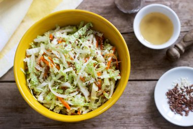 Lahana salatası, havuç ve ahşap zemin üzerinde büyük bir tabakta mayonez bulunan çeşitli otlar. Seçici odak.