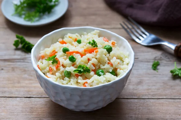 Вегетарианское блюдо из риса с овощами и зеленым горохом на деревянном фоне . — стоковое фото