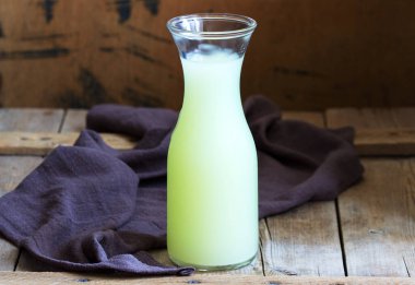 Ahşap bir arka planda cam bir şişede soğuk süt. Seçici odak.