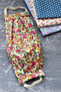 Ev yapımı koruyucu maske ve gri arka planda kumaş parçaları. Seçici odak.