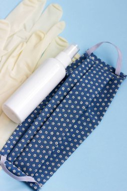 Kişisel koruyucu ekipman maskesi, eldivenler ve mavi arka planda dezenfektan. Seçici odak.