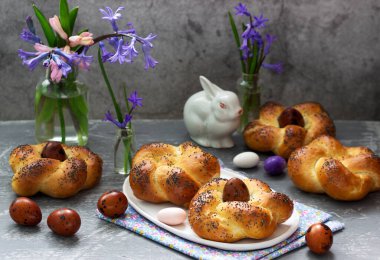 Paskalya çörekleri, renkli yumurtalar ve çiçekler gri beton arka planda. Seçici odak.