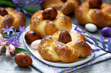 Paskalya çörekleri, renkli yumurtalar ve çiçekler gri beton arka planda. Seçici odak.