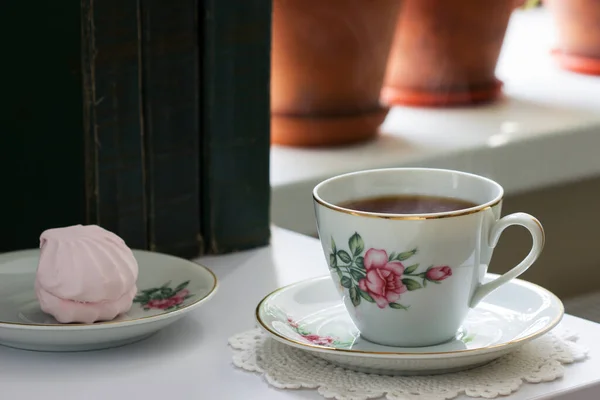 Té en una taza vintage, malvaviscos en un platillo vintage y libros antiguos sobre un fondo claro . — Foto de Stock