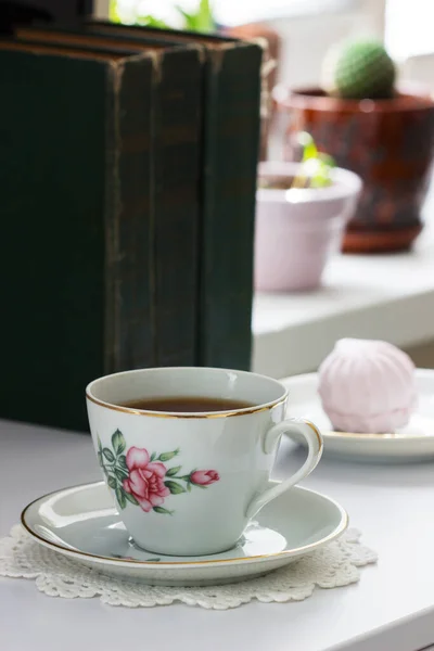 Tee in einer Vintage-Tasse, Marshmallows auf einer Vintage-Untertasse und alte Bücher auf hellem Hintergrund. — Stockfoto