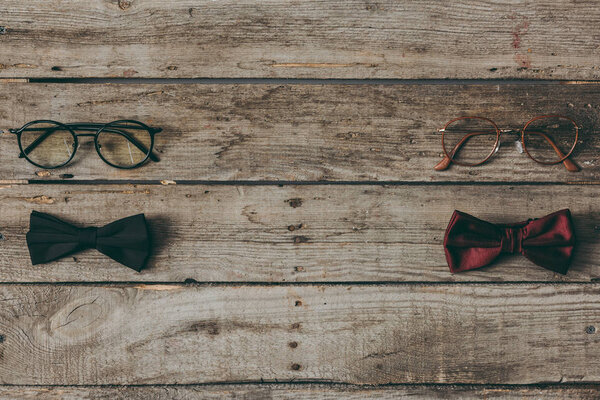 stylish bow ties and eyeglasses on tabletop