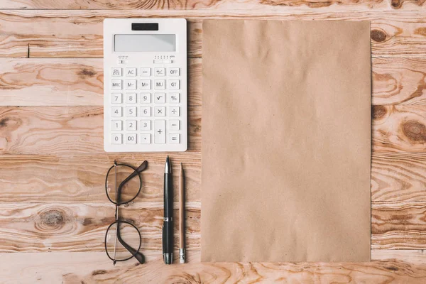 Calculator with eyeglasses and office supplies on tabletop — Free Stock Photo